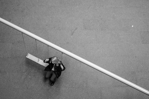 Overhead view of a person in dark clothing lying on concrete next to a white diagonal line.
