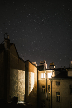 Parisian building facade illuminated at night beneath a starry sky.