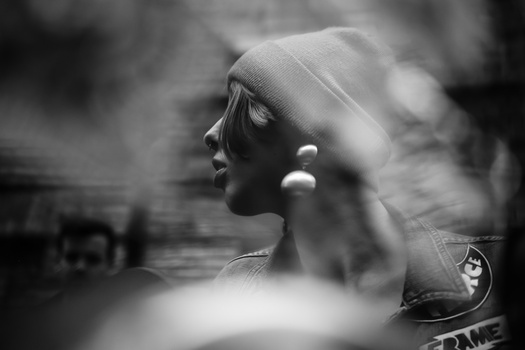 Profile of a woman wearing a head wrap and pearl earrings in soft-focus black and white portrait.