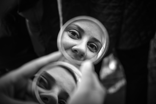 Black and white portrait of a person's face framed within circular distortions, shot from above looking upward.