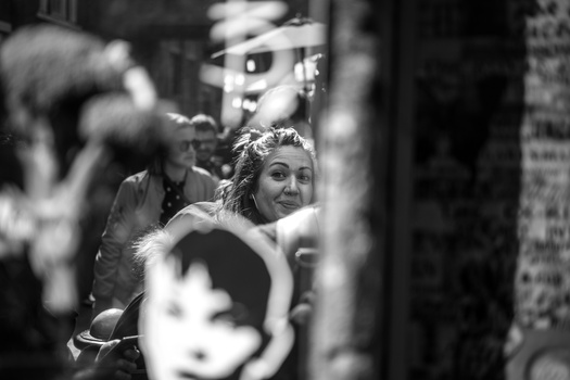 Woman in crowd looking toward camera with selective focus in black and white street photography.