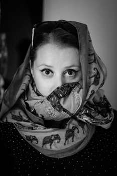 Black and white portrait of a woman with patterned fabric draped over her head and face.