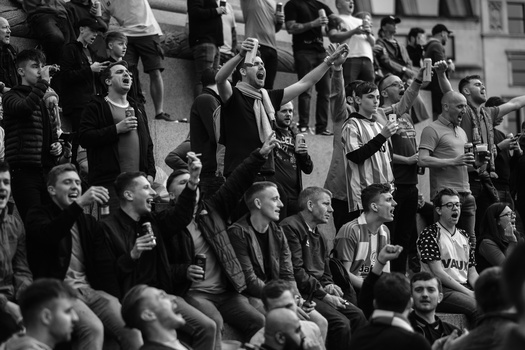 Crowd of spectators at a sporting event, many holding phones and cameras aloft to record the action.