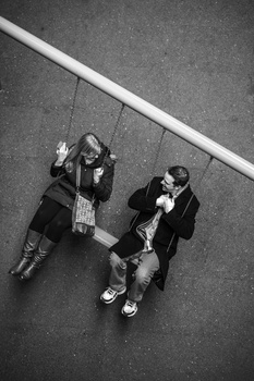 Two people photographed from above lying on pavement next to a white stripe, shot in black and white.