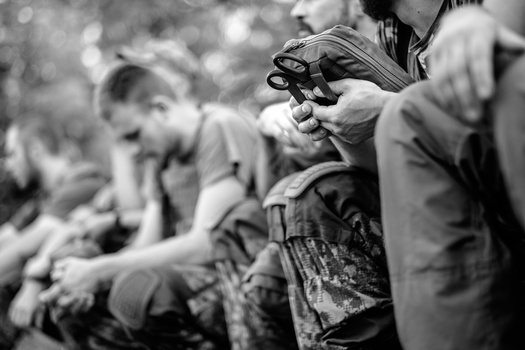 Photographer holding a camera with telephoto lens, surrounded by blurred people in background.