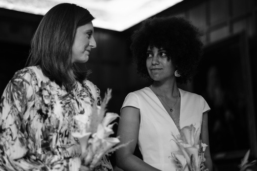 Two women in conversation, captured in black and white profile view against a dark interior background.