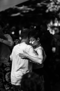 Man and woman embracing outdoors in black and white photography.