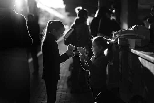 Children silhouetted against bright backlighting on a nighttime street.