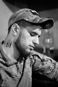 Profile portrait of bearded man wearing baseball cap in black and white.