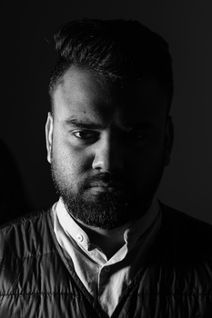 Portrait of a bearded man with dramatic side lighting against a dark background.
