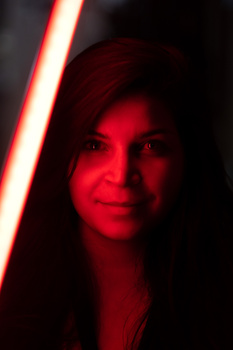 Portrait of a woman illuminated by red neon light against a dark background.