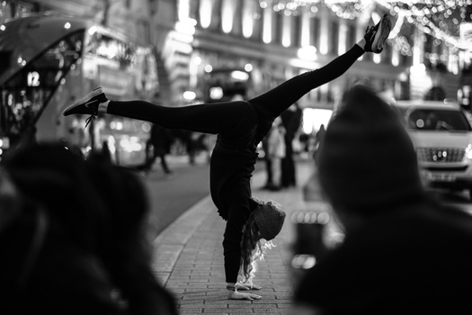 Street performer doing a handstand on an urban sidewalk during daytime.