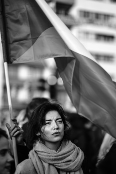 Young person holding a flag at a protest or demonstration, photographed in black and white.