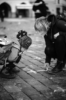 Woman crouching beside a scooter, examining or photographing its details in black and white.