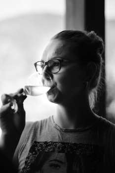 Person wearing glasses in profile, holding a cigarette to their mouth against a blurred background.