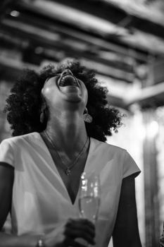 Woman with curly hair tilting head back in contemplative pose, shot in black and white.