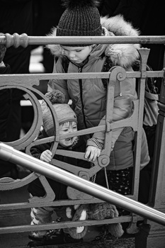 Child seated in metal framework structure, shot in black and white with shallow depth of field.