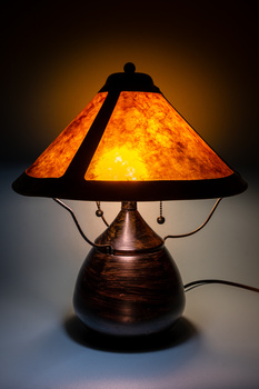 Vintage table lamp with amber glass shade and bronze metal base, illuminated from within.
