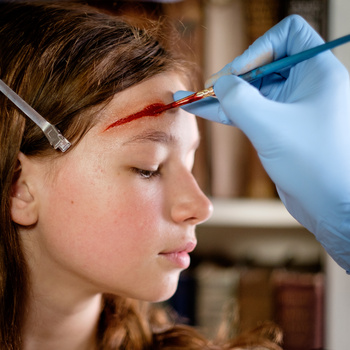 Close-up profile of a person receiving eyebrow microblading treatment with a precision brush.