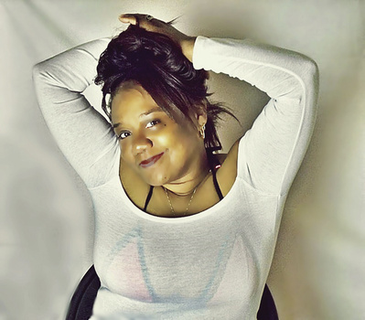 Woman posing overhead shot with arms raised behind head, wearing white long-sleeve shirt.