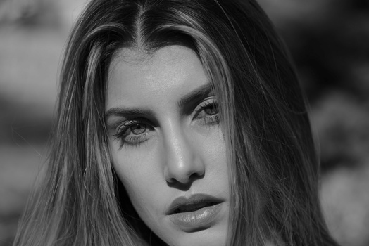 Black and white portrait of a woman with long dark hair looking directly at camera.