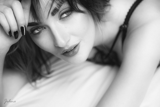 Black and white portrait of a woman with short dark hair and bangs, resting her head on her hand with a contemplative expression.