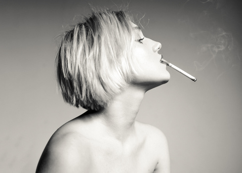 Black and white profile portrait of a person with short blonde hair smoking a cigarette.