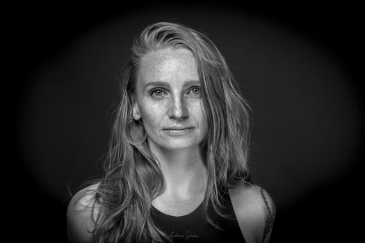 Black and white portrait of a woman with long hair against a dark background.
