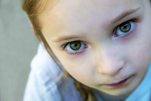 Young child with striking blue-green eyes looking directly at camera with gentle expression.