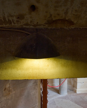 Industrial pendant lamp with black dome shade casting warm yellow light on textured concrete ceiling.