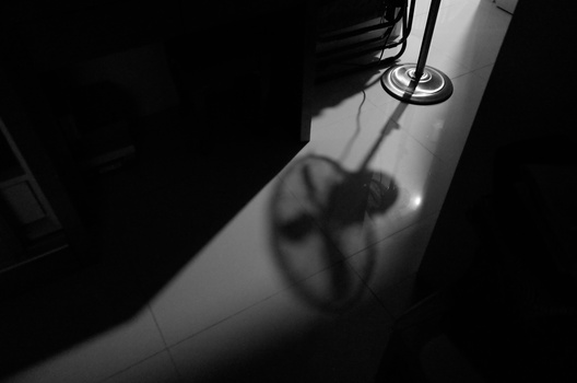 Hand casting shadow on sunlit floor beneath a skylight opening.