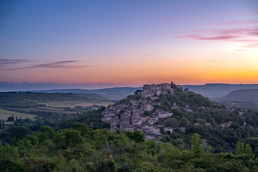 Hilltop village with clustered stone buildings nestled against a twilight sky at golden hour.