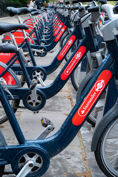 Row of red and blue docked bicycles lined up in an urban bike-sharing station.