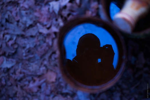 Silhouetted figure framed through a circular opening against blue sky.