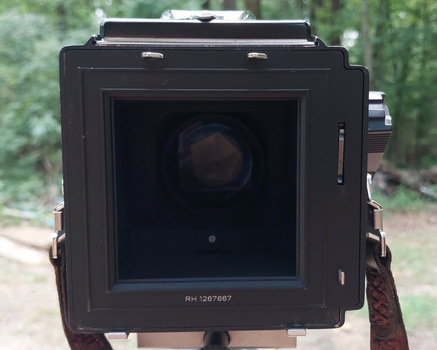 Large format film camera with open back showing film plane and serial number marking.