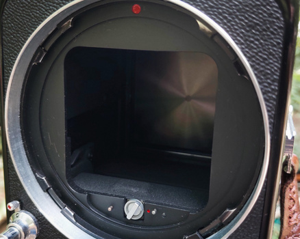 Interior view of a camera body showing the mirror box and focusing screen with control buttons visible at the base.
