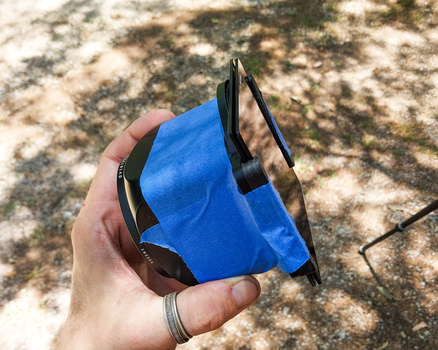 Hand holding blue microfiber cleaning cloth with sunglasses on concrete surface.