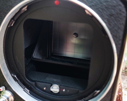 Interior view of a camera body showing the mirror box and focusing screen with visible grid lines.