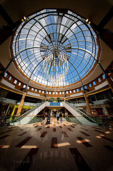 Circular dome ceiling with geometric glass panels creating radial symmetry above a modern interior atrium.
