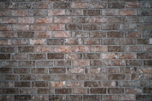 Weathered brick wall with varied red and brown tones and visible mortar joints.
