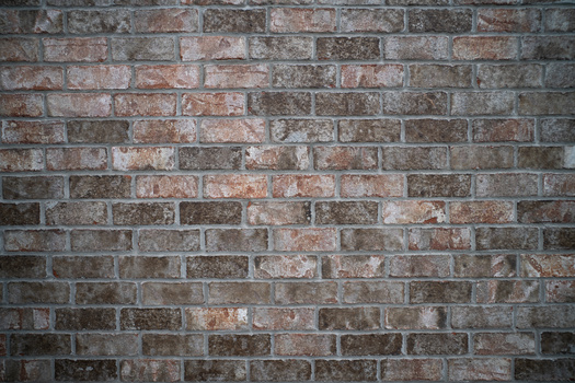 Weathered brick wall with varied red, brown, and gray tones in running bond pattern.
