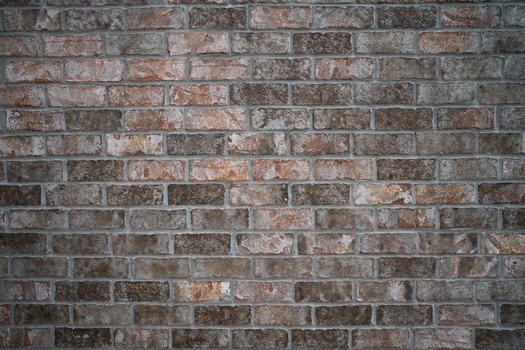 Weathered brick wall with varied reddish-brown and gray tones throughout the surface.