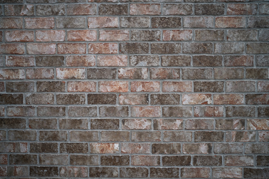 Weathered brick wall with varied red, brown, and gray tones and visible mortar joints.
