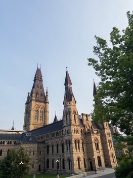 Gothic Revival stone building with twin spires lit by golden afternoon sunlight against clear blue sky.