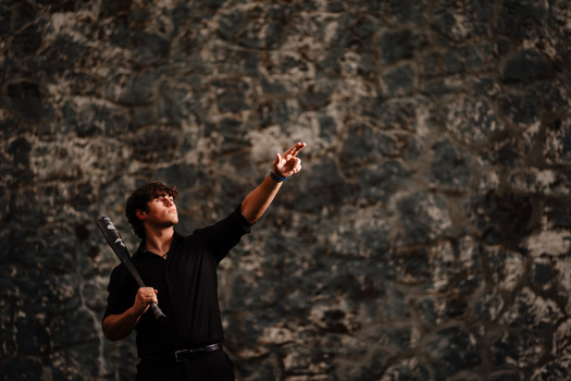 Person in black shirt reaching upward against weathered textured wall with dramatic side lighting.
