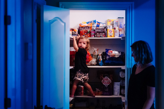 Woman viewing illuminated closet display with child's toys and items arranged on shelves.