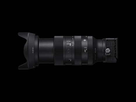Black telephoto zoom lens with hood and focus ring displayed horizontally against dark background.
