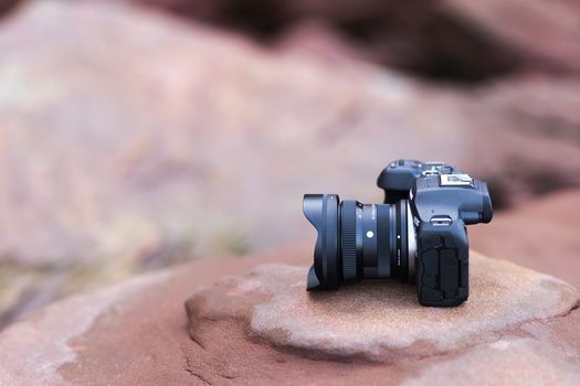 Mirrorless camera with attached wide-angle lens positioned on weathered sandstone rock.
