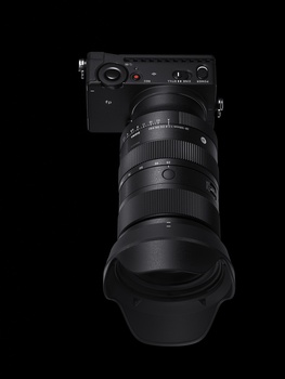 Mirrorless camera with attached telephoto zoom lens against black background.