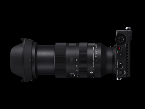 Mirrorless camera with telephoto lens and lens hood mounted on black background.